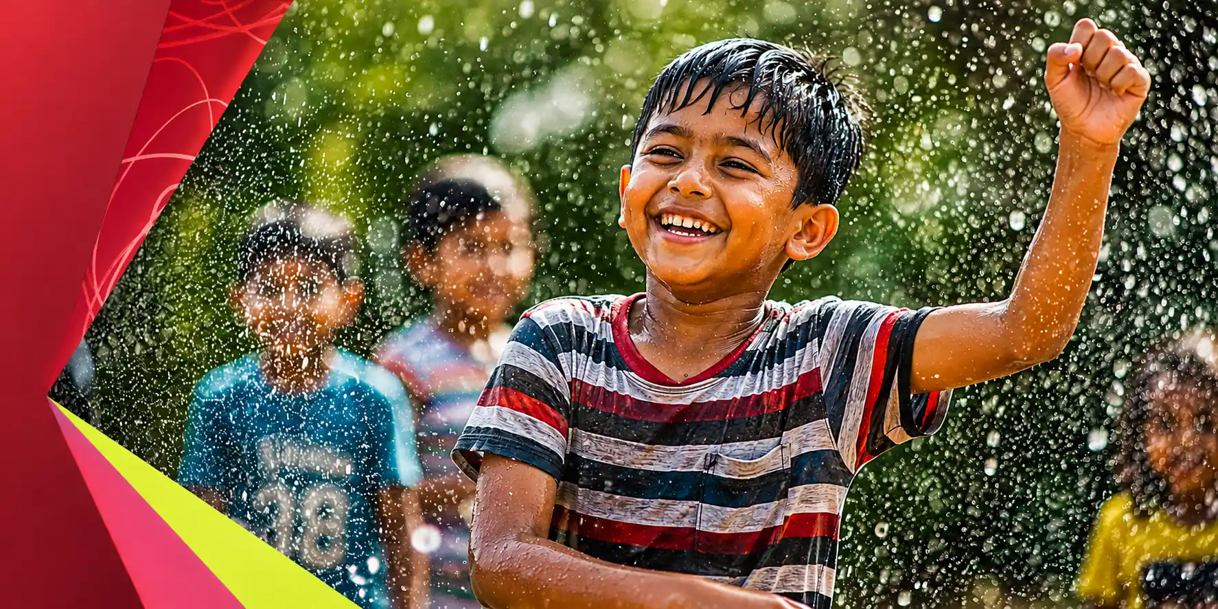 A boy laughing with his eyes closed and one fist raised, drenched by a spray of water, with other children playing behind him.