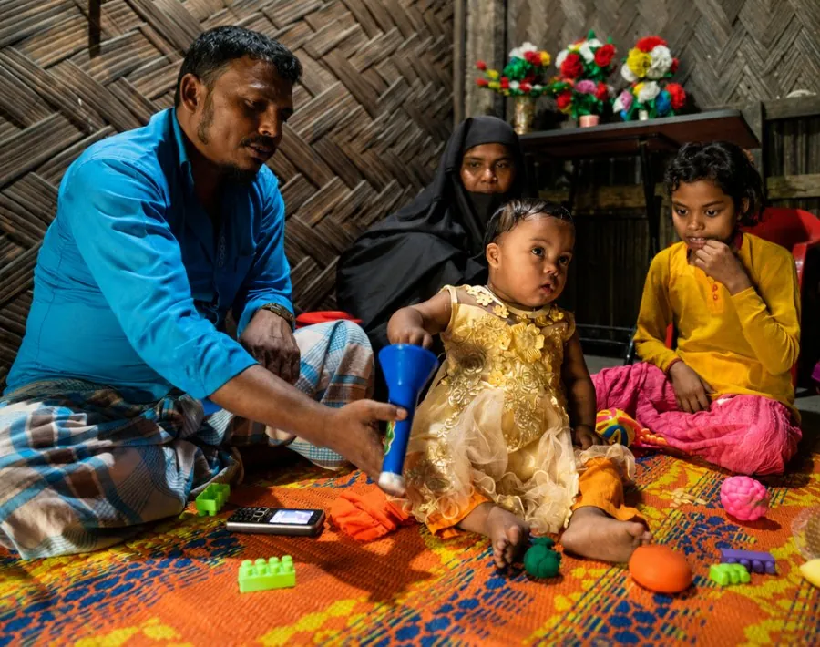 A father playing with his child at home while the family watches