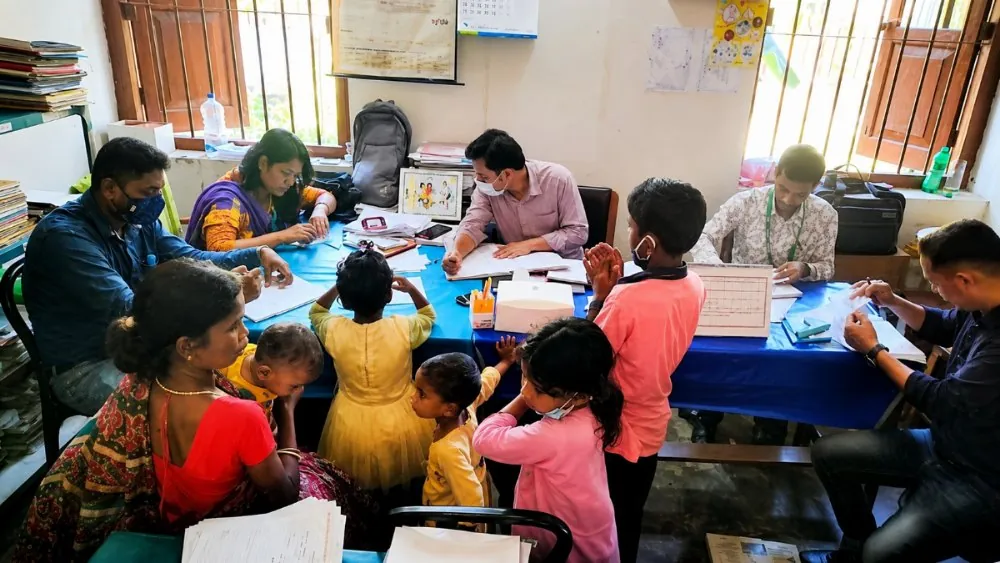 A crowded assessment camp where therapists fill in paper forms